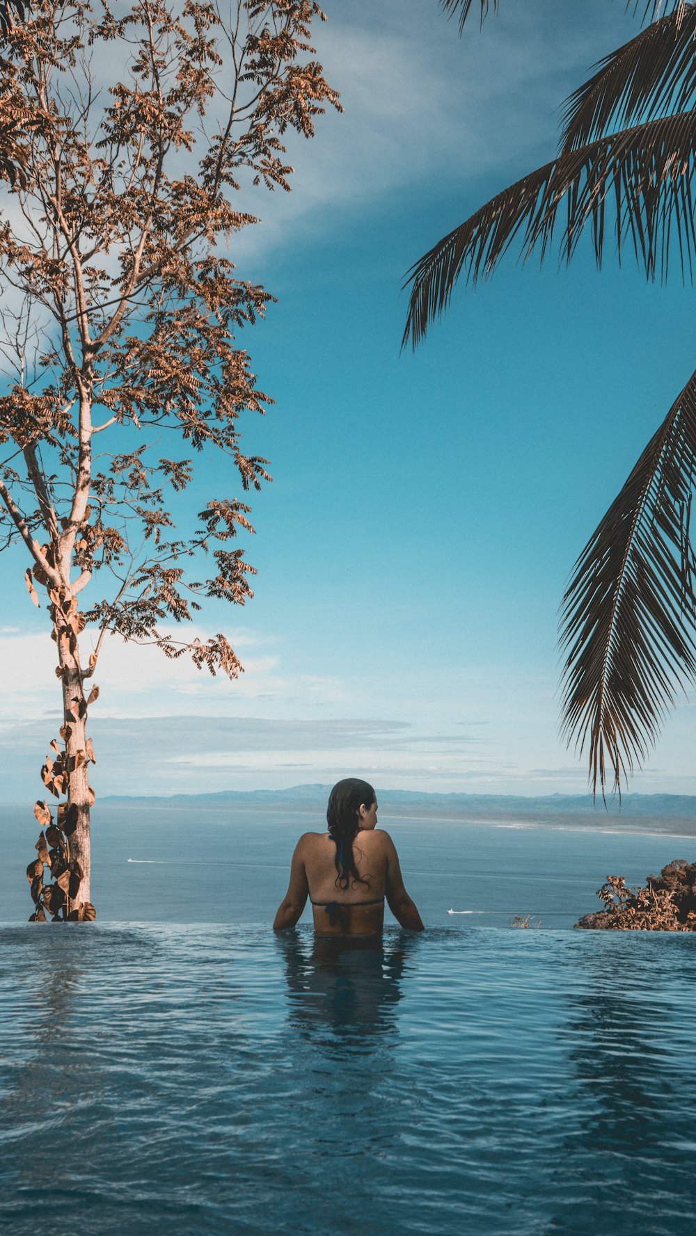 Model in an infinity pool above the ocean